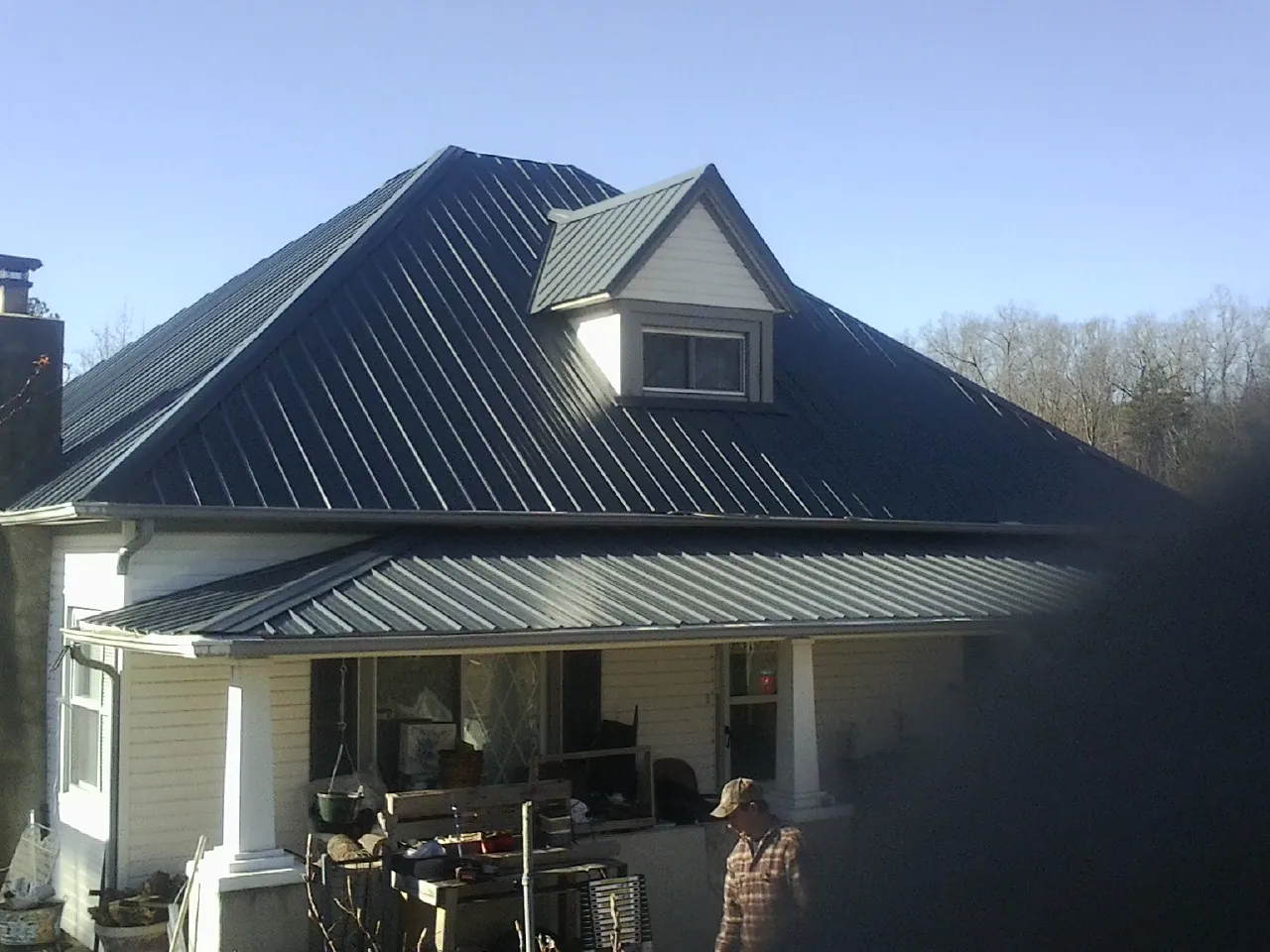 Dark blue standing seam metal roof with a dormer above a front porch in Newport