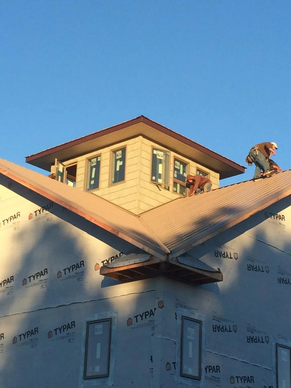 Roofers working around a rooftop cupola on a new metal roof at sunset — Roof Waterproofing in Newport by Roofing Brothers